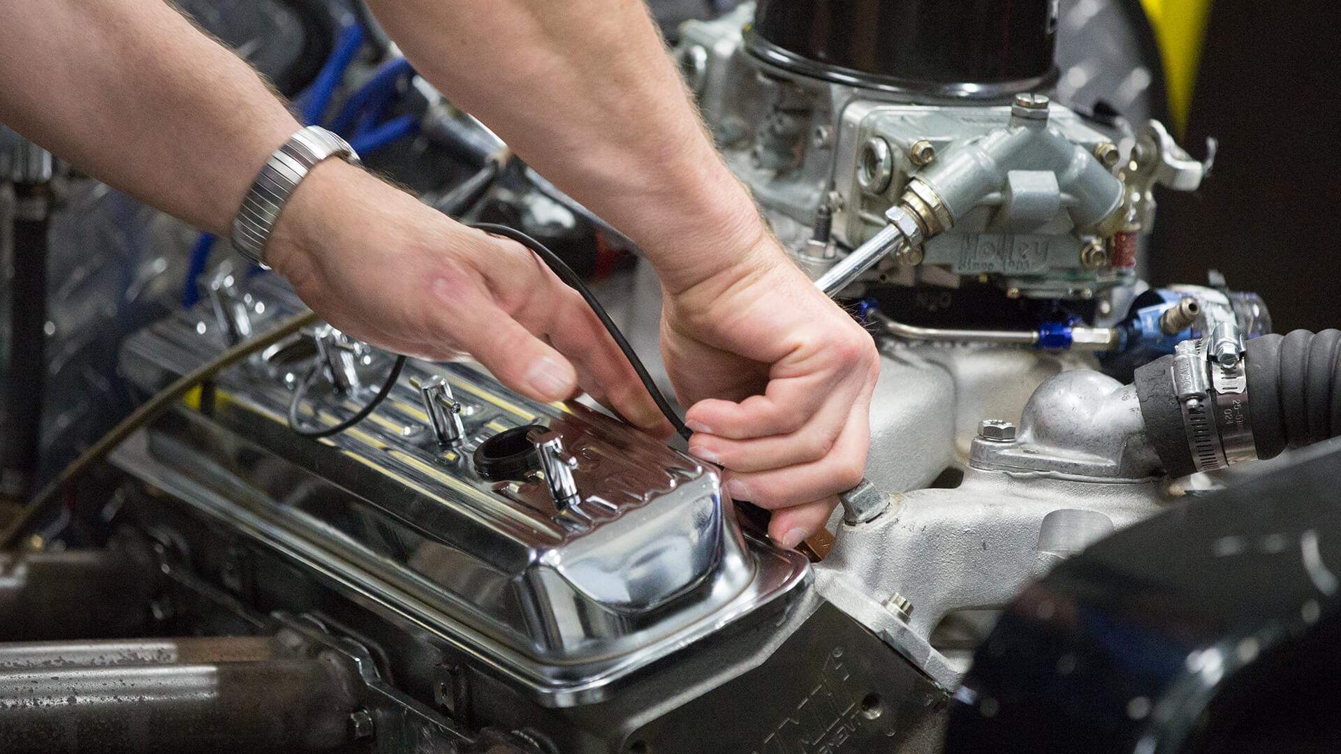 Students hands working on an engine